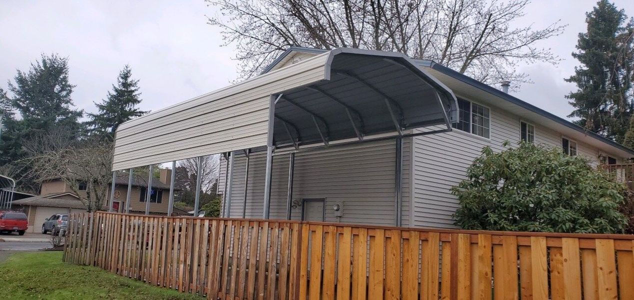A house with a carport and a wooden fence in front of it.