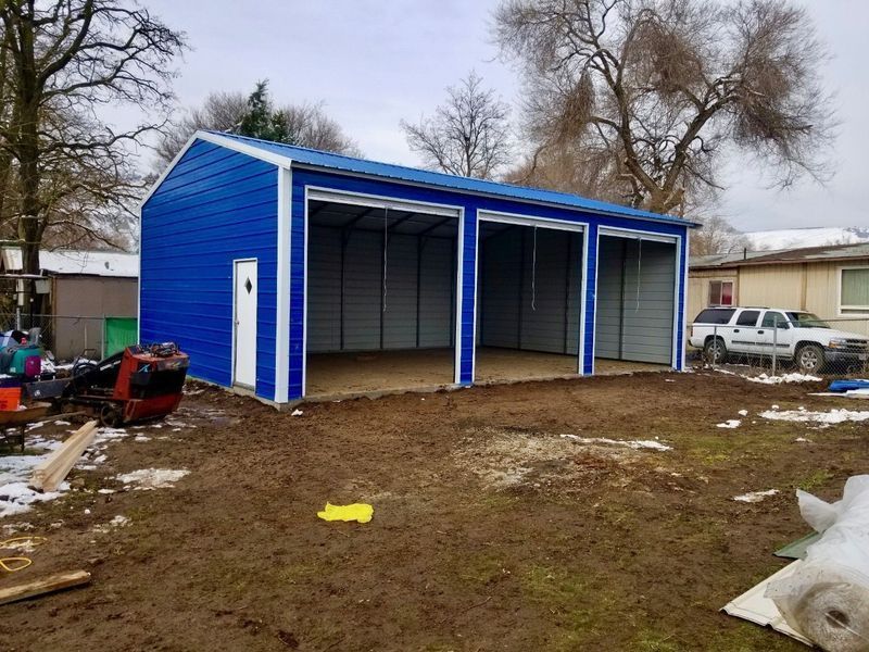A blue and white garage is being built in a yard.
