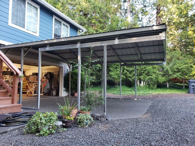 A blue house with a carport in front of it.