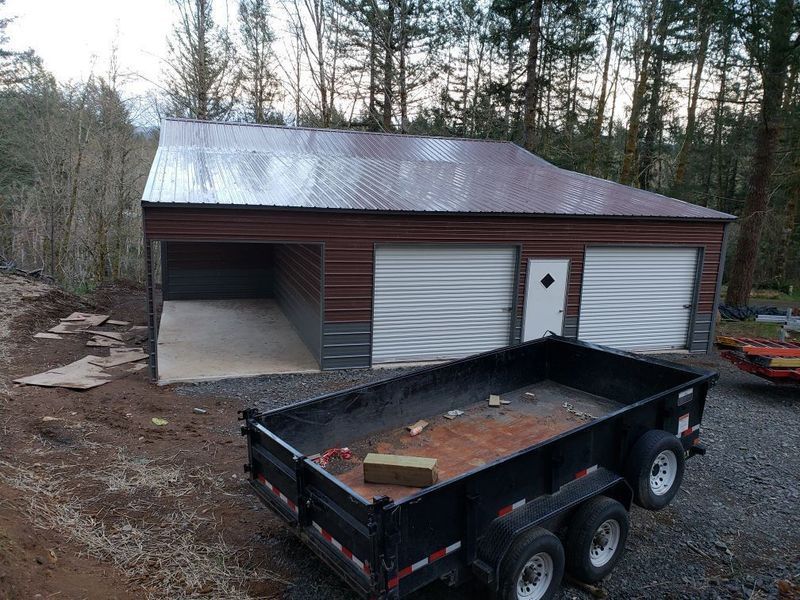 A dumpster is parked in front of a garage.