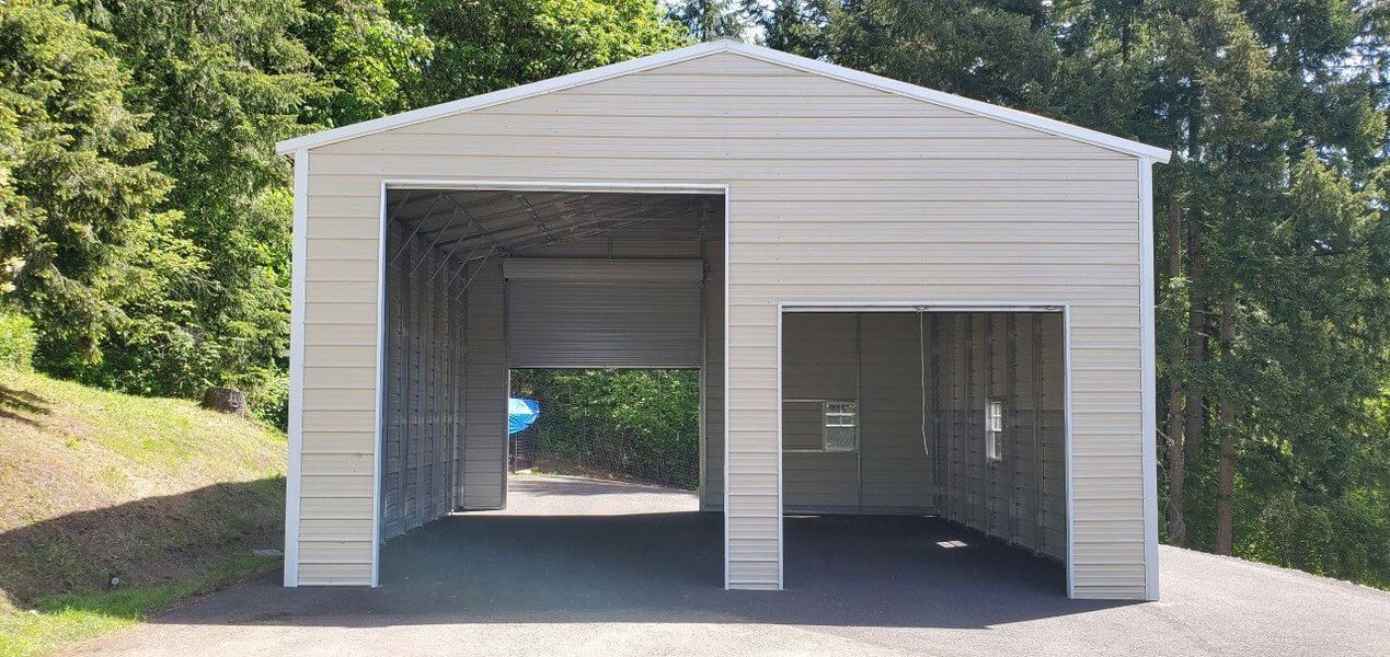 A white garage with two garage doors is sitting on top of a dirt hill.