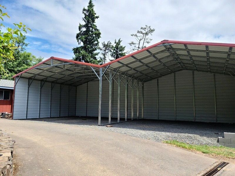 A green house with a carport attached to it.