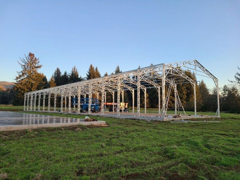 A large metal structure is being built in a grassy field.