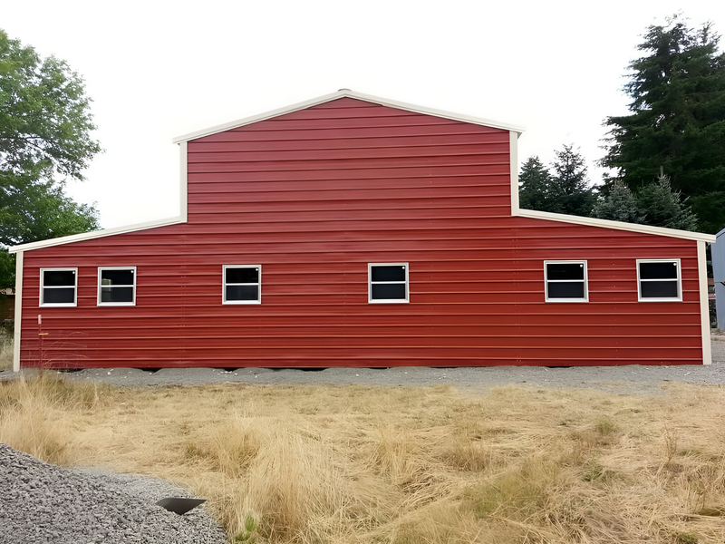 A large red barn with white trim is sitting in the middle of a field.