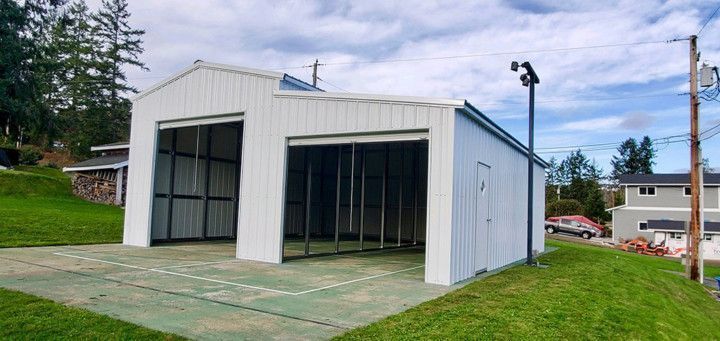A white garage is sitting on top of a grassy hill.
