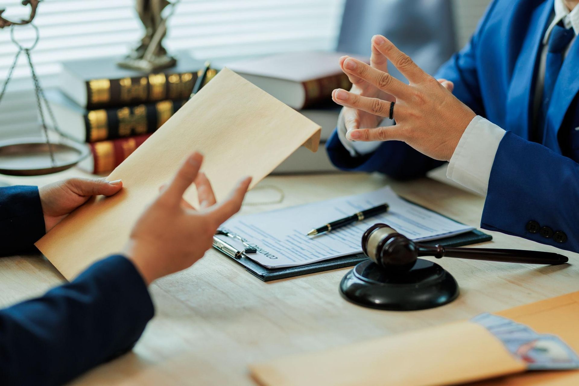 Two people discuss a document at a desk with a gavel and notebook in an office setting