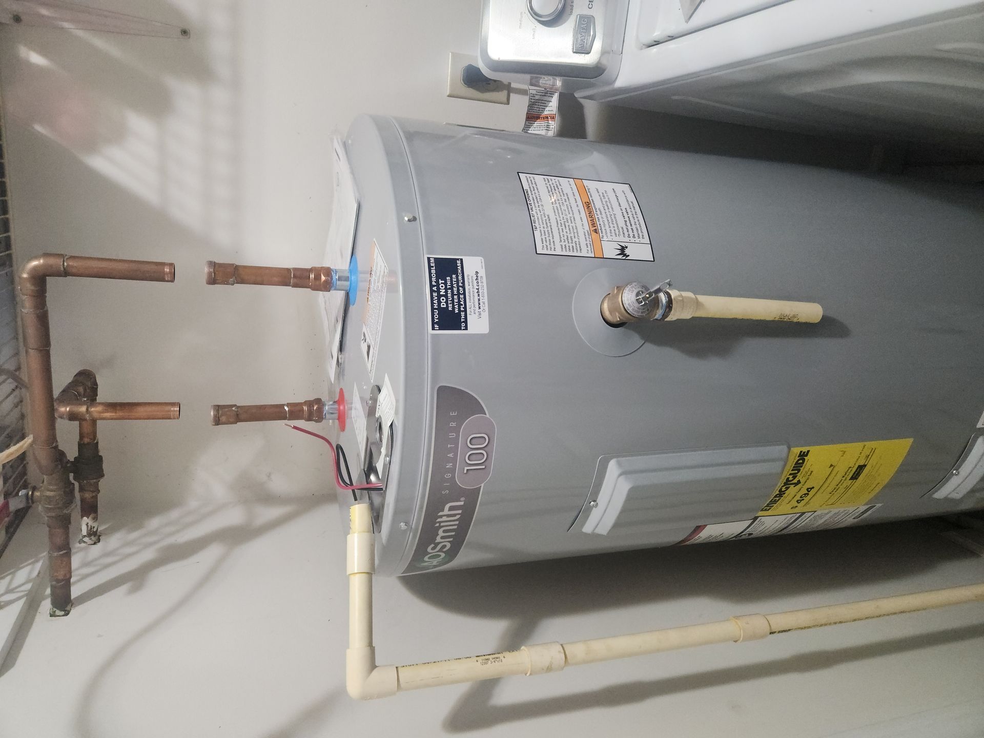 Gray water heater with copper and PVC pipes in a utility area