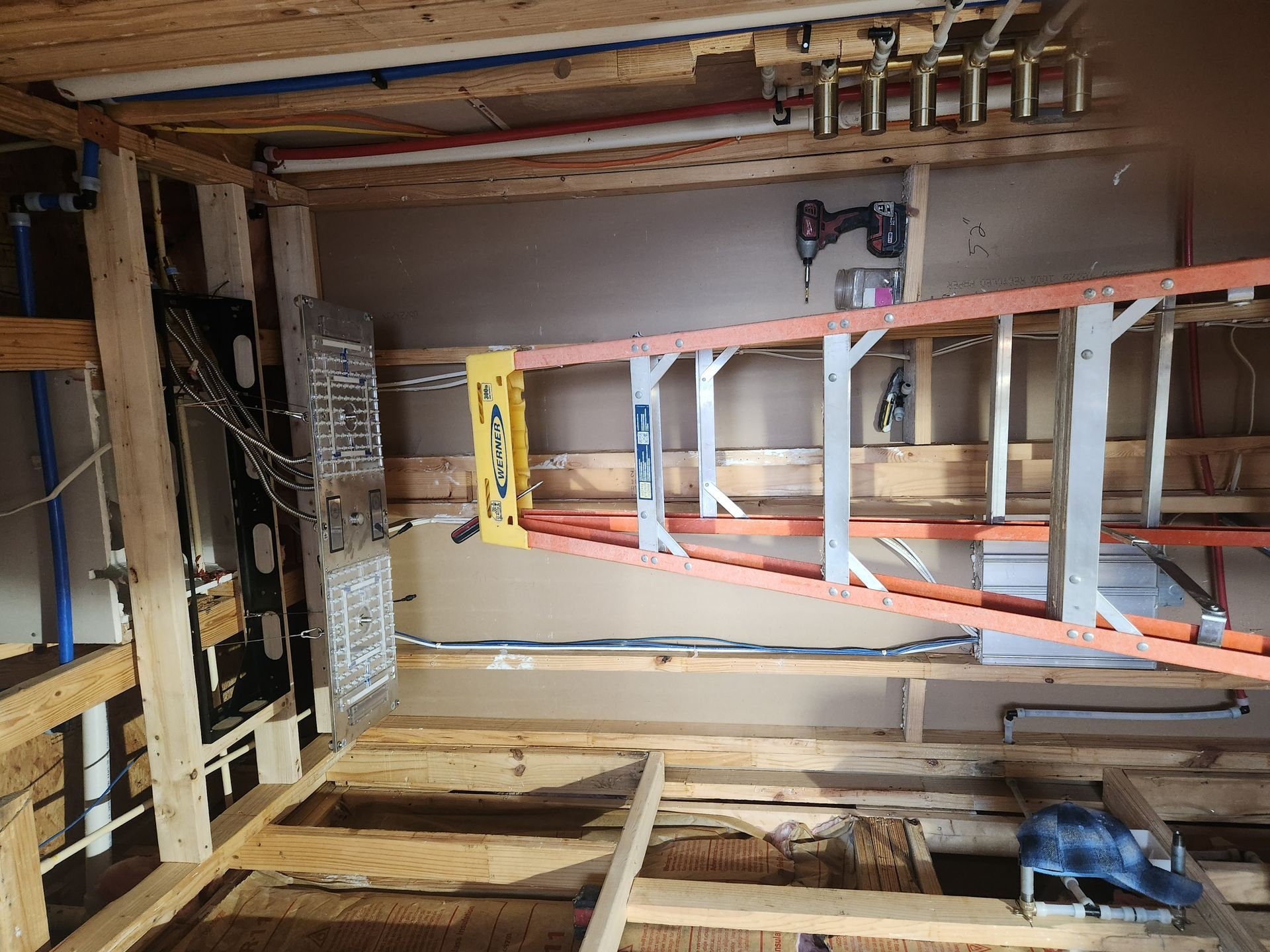 Partially framed interior room with exposed wood, electrical panel, and pink insulation on the wall