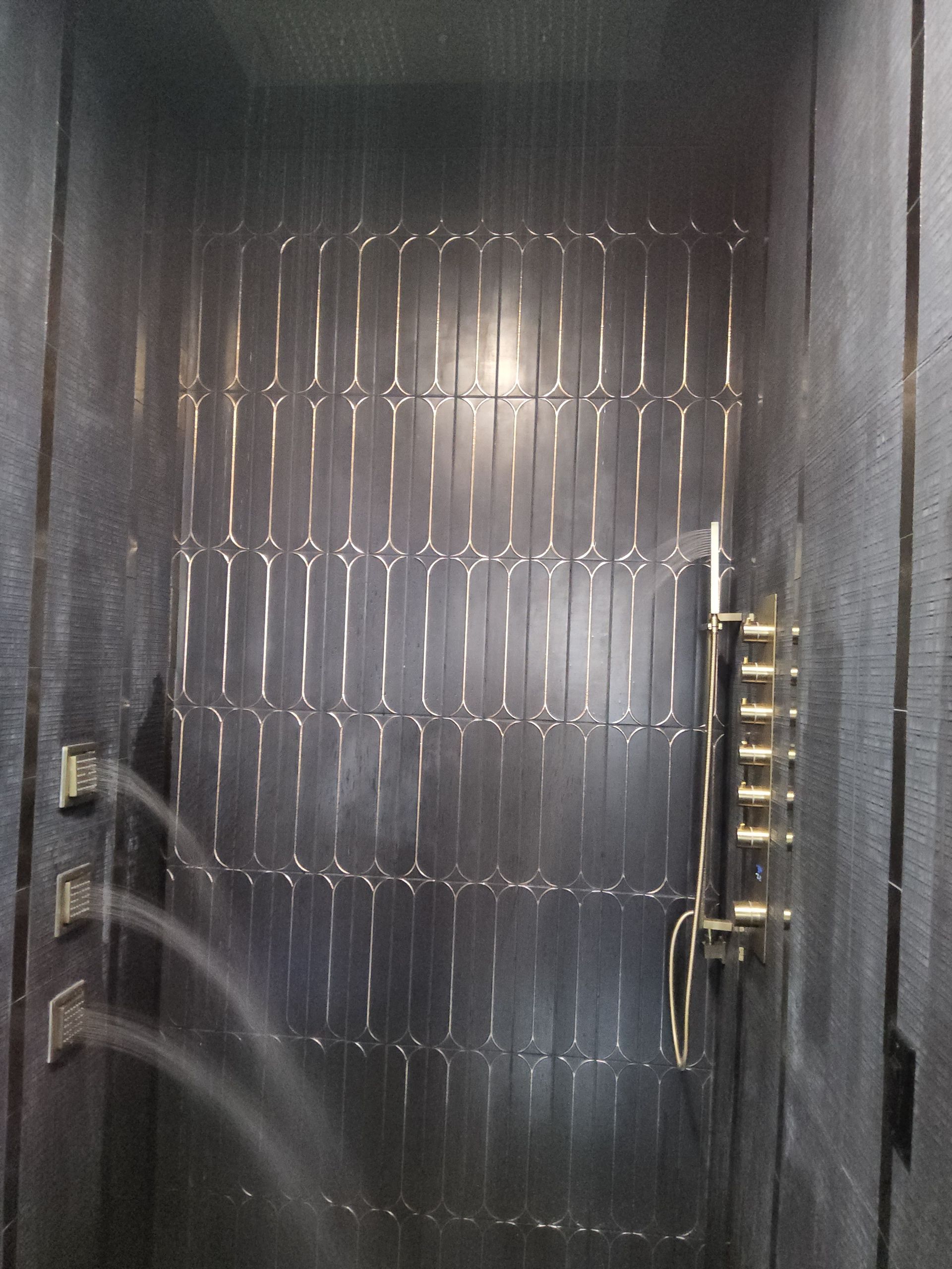 Metal front door with frosted patterned glass and a gold handle, slightly open in a dim hallway