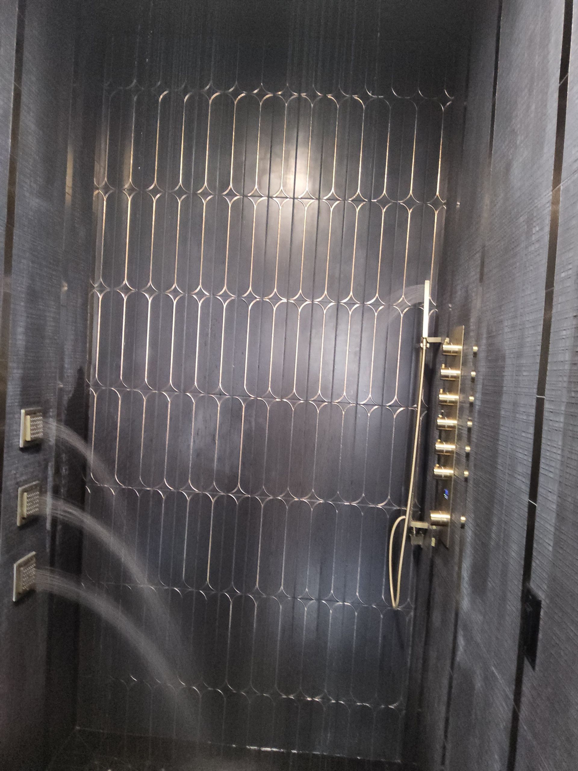Closed metal security gate with a bright reflection, viewed in a narrow hallway.