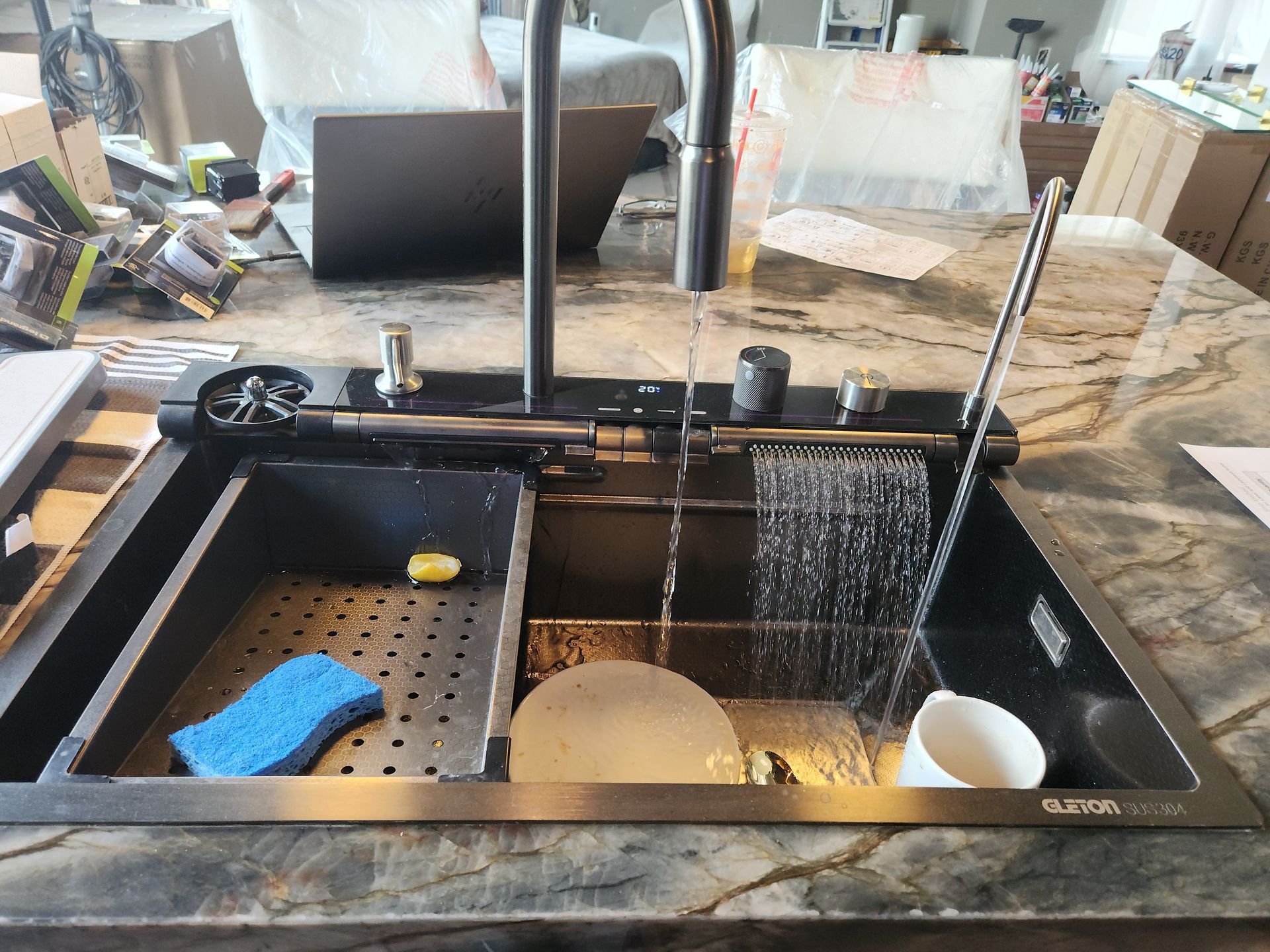 Kitchen sink with dishes, sponge, and running water under a faucet in a messy countertop setting