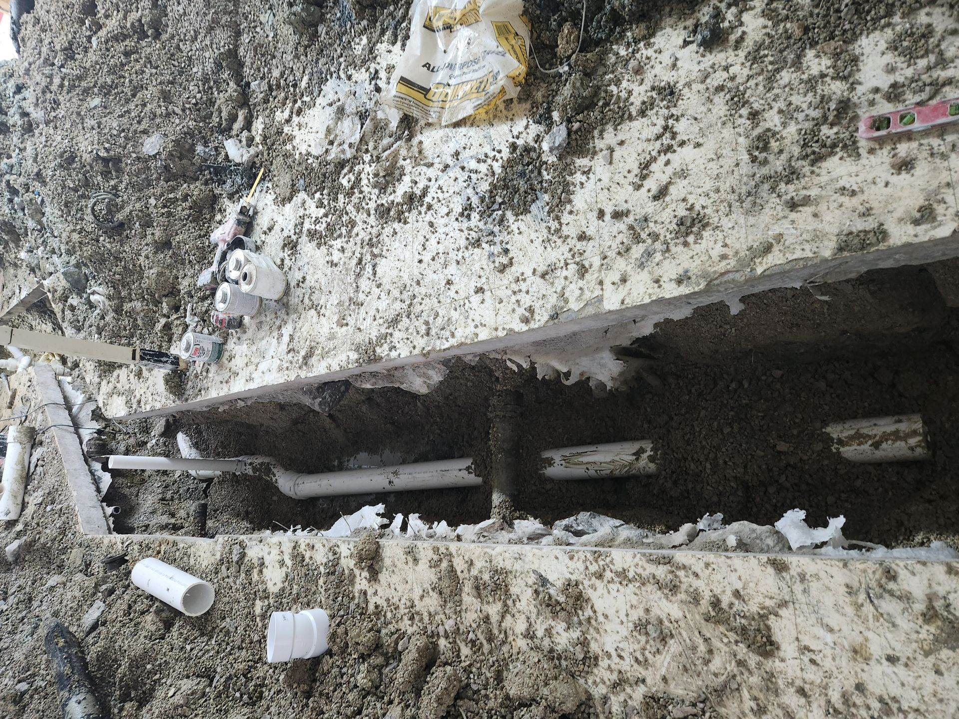 Snow-covered concrete trench with dark metal beams and debris along a wall