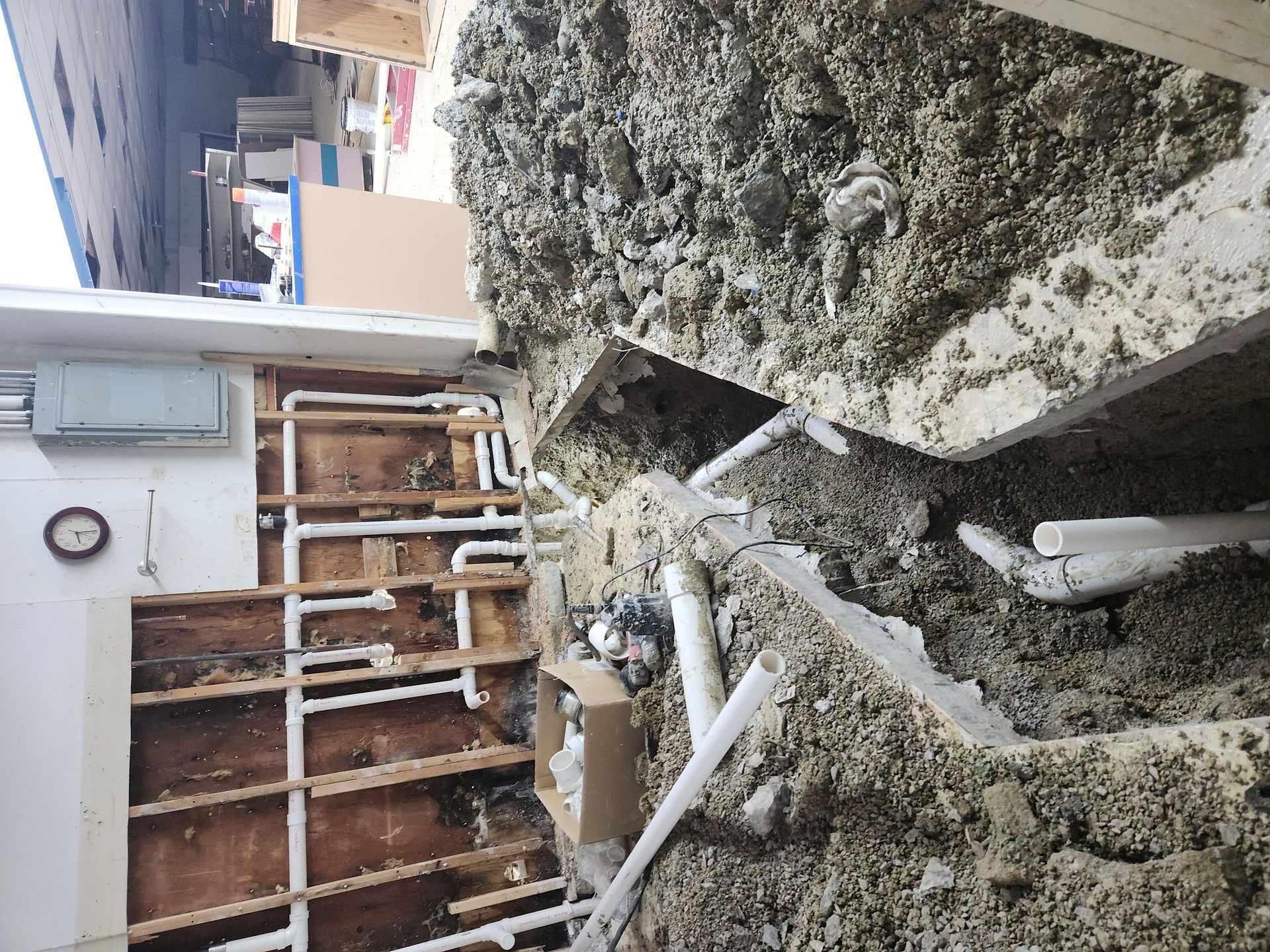 Collapsed concrete wall with exposed pipes and debris beside a building exterior