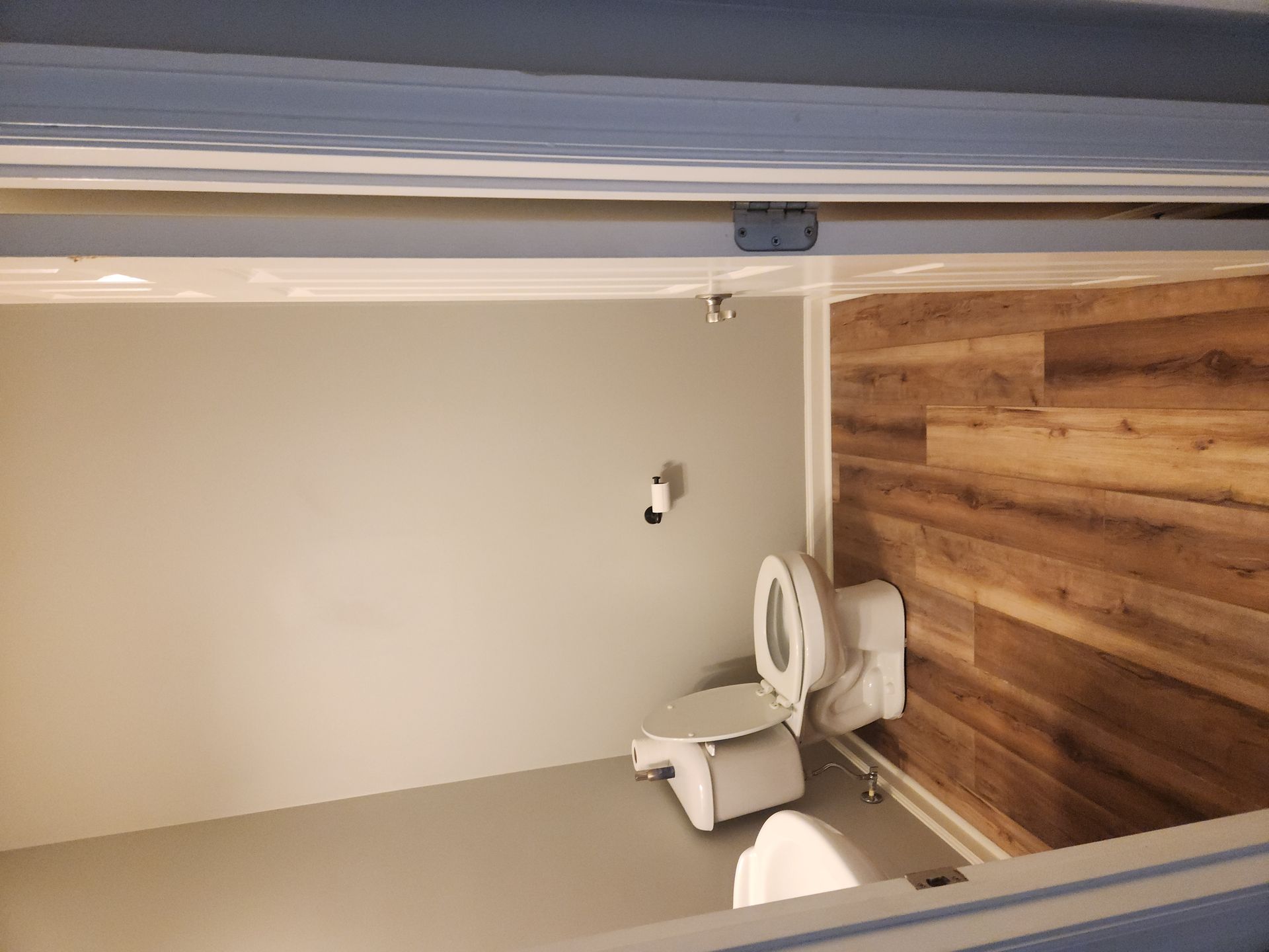 Upside-down bathroom with toilet, wood floor, and beige walls