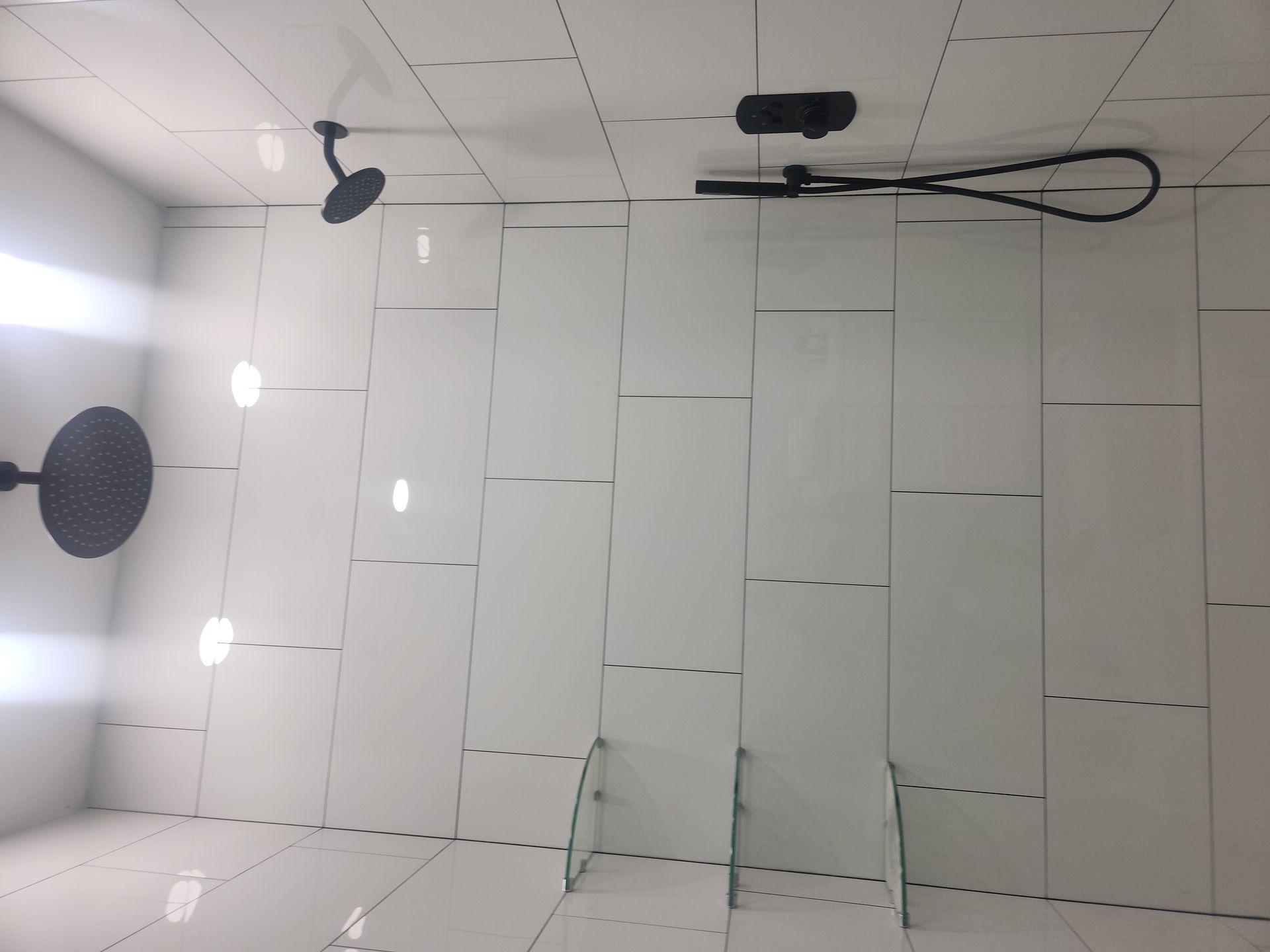 White tiled ceiling with recessed lights, vents, and hanging black cables in a room