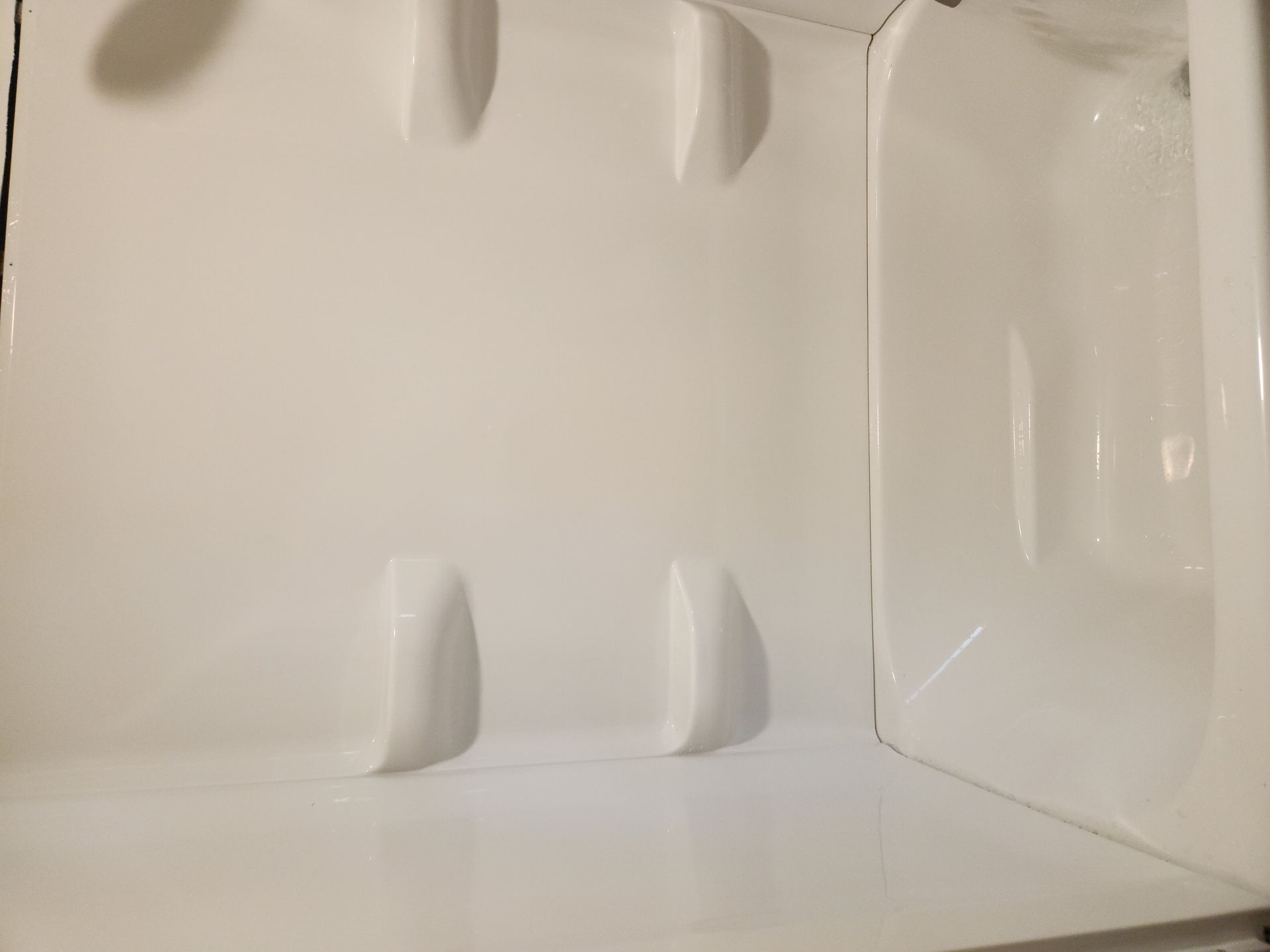 Empty white plastic container interior with molded corners and shallow support ridges