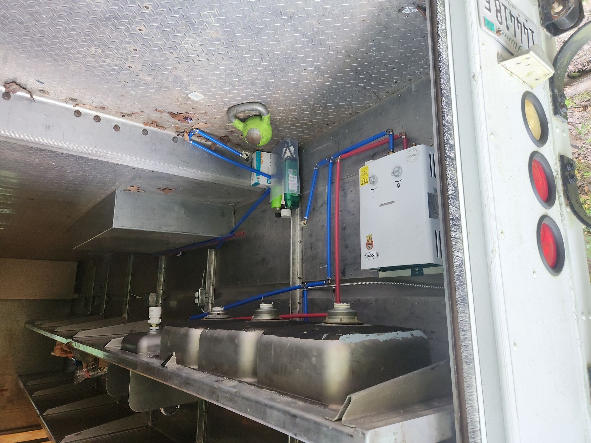 Industrial metal compartment with pipes, valves, and control panel inside a machine or tank.