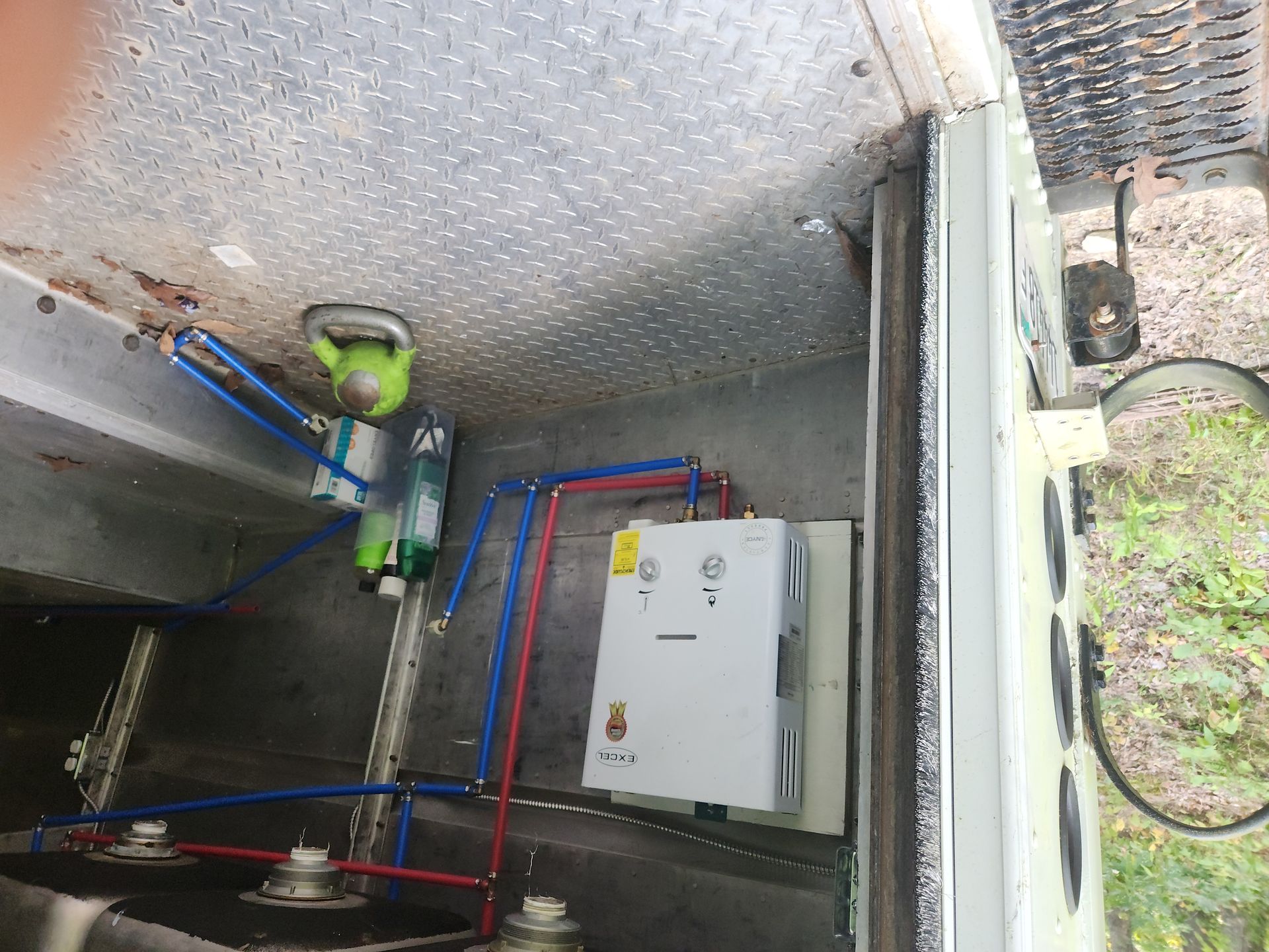 Utility room with pipes, valves, and a white electrical control box on a metal wall