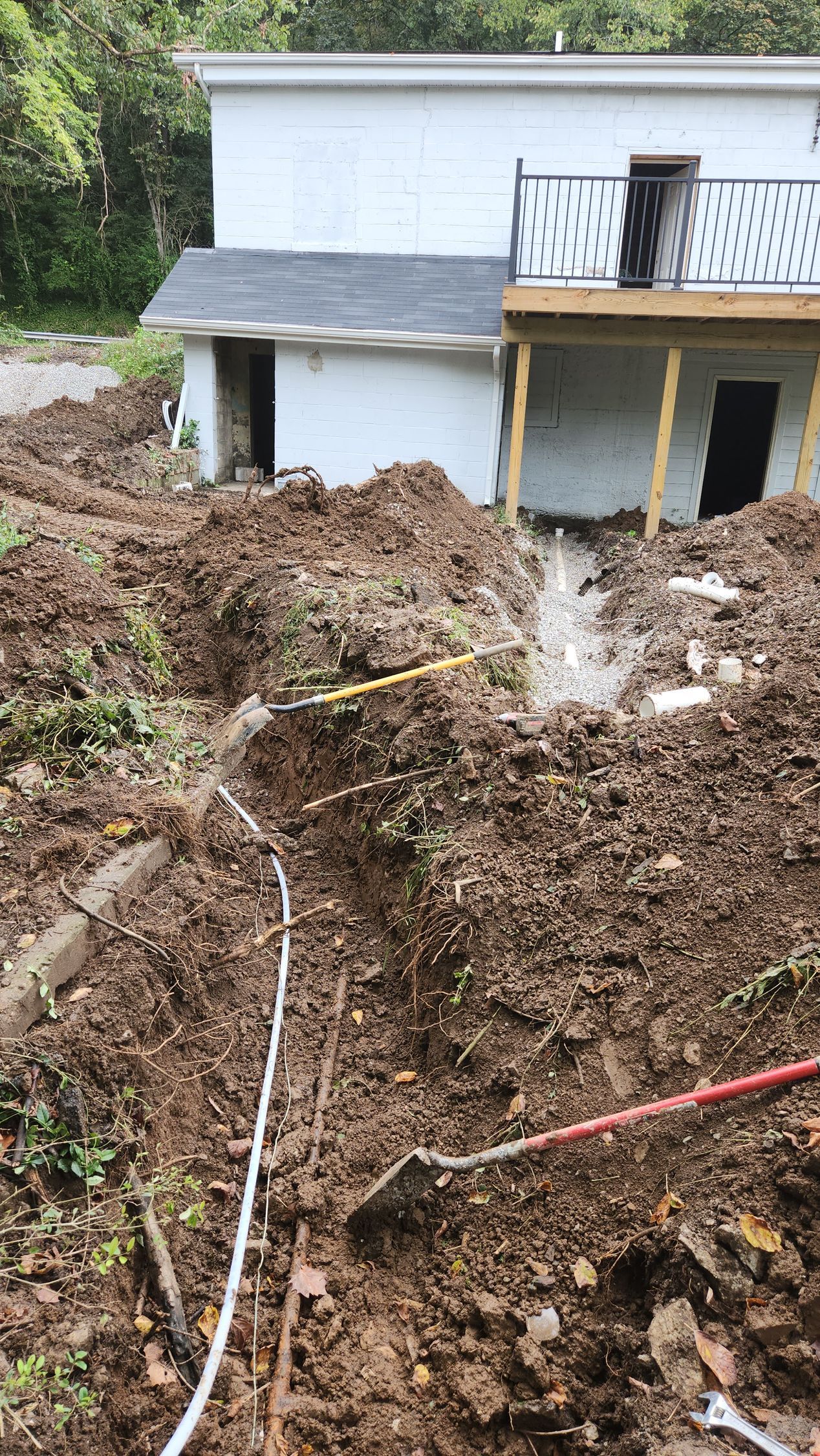 Backyard slope collapse with exposed mud and debris near a white house and deck.