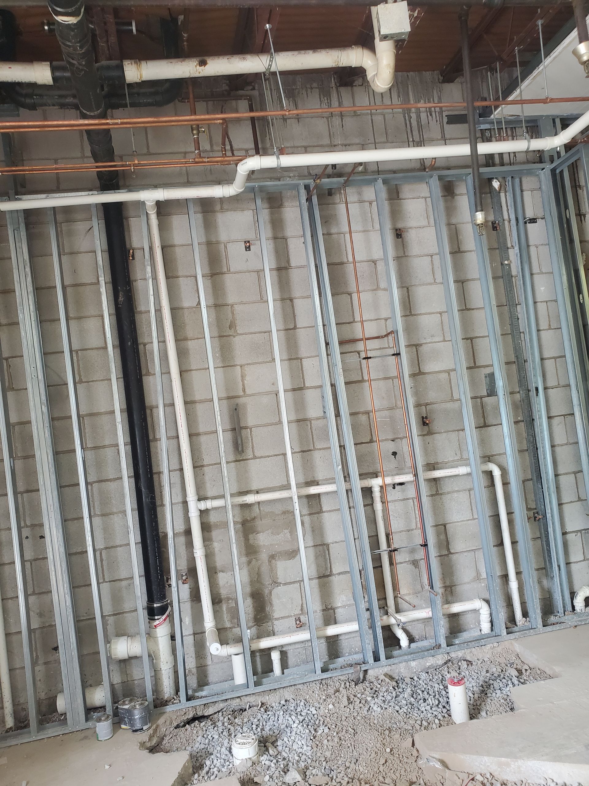 Exposed ceiling framing and ductwork in an unfinished construction interior with debris on the floor