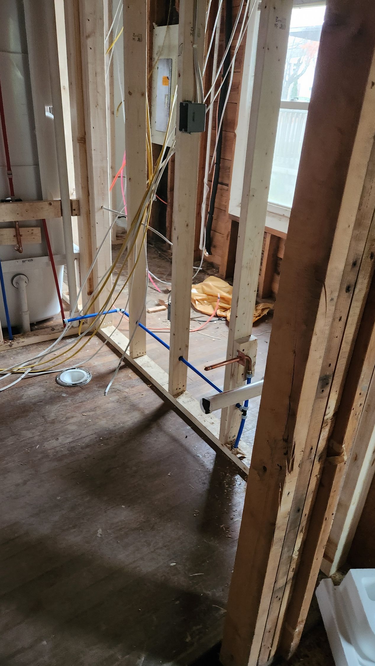 Partially stripped interior wall framing in a construction site with exposed studs and wiring