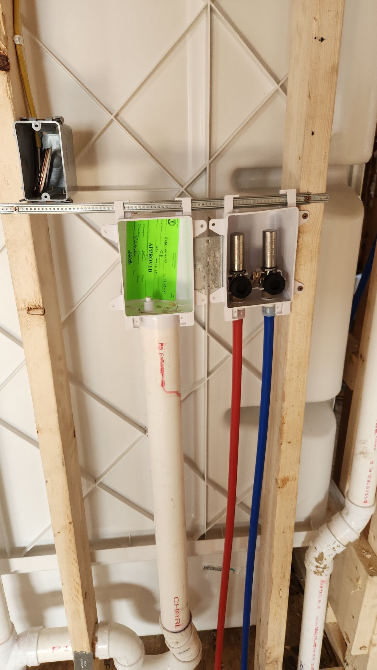Wall-mounted utility piping and valves, including a bright green panel and red and blue pipes.