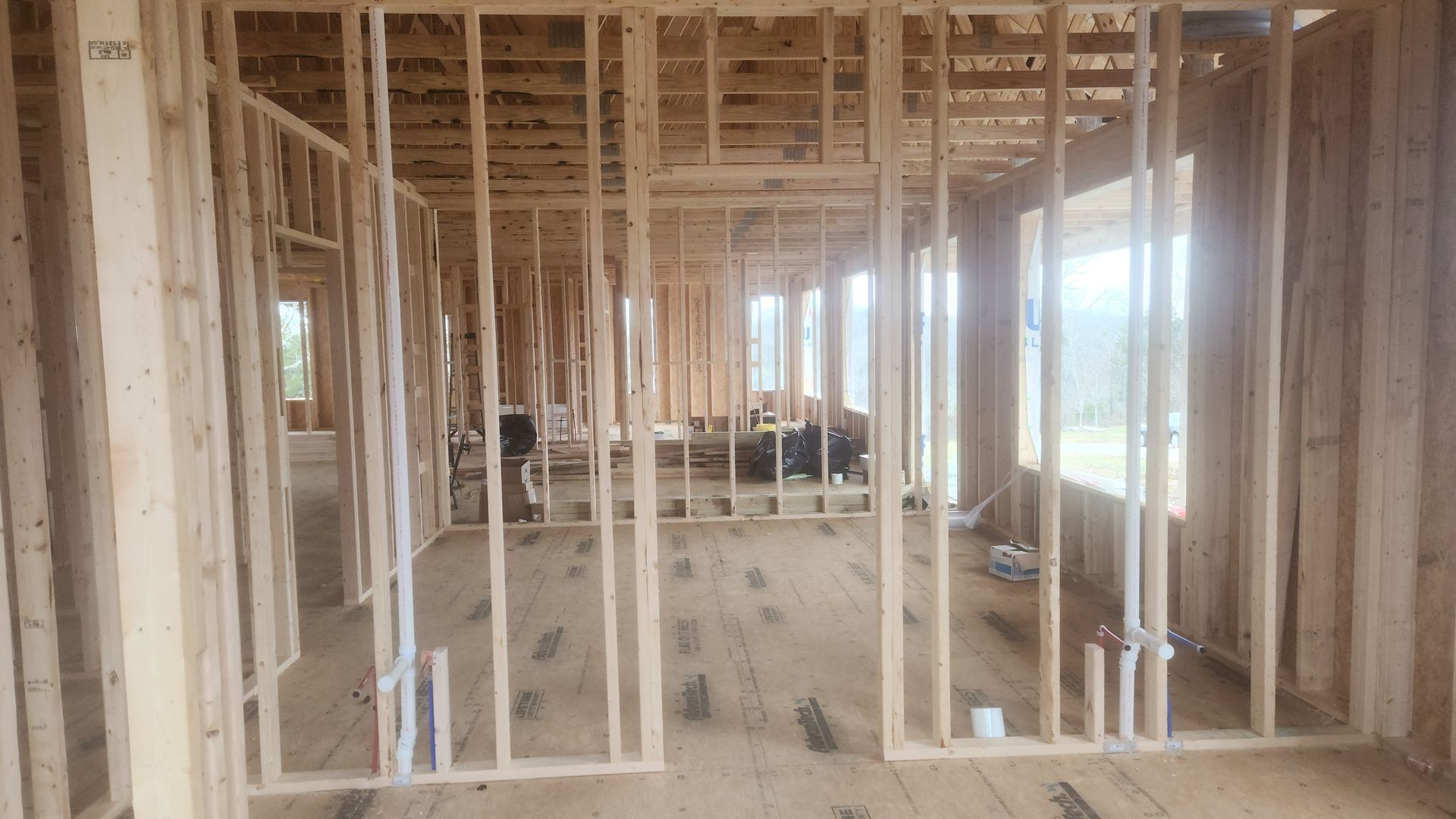Framed wooden interior of a house under construction, with exposed studs and unfinished floors.