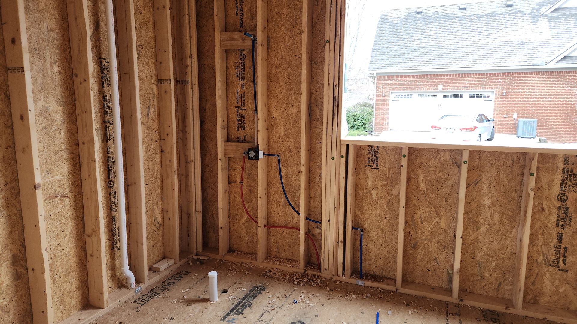 Unfinished wooden room framing with exposed studs and a large window opening