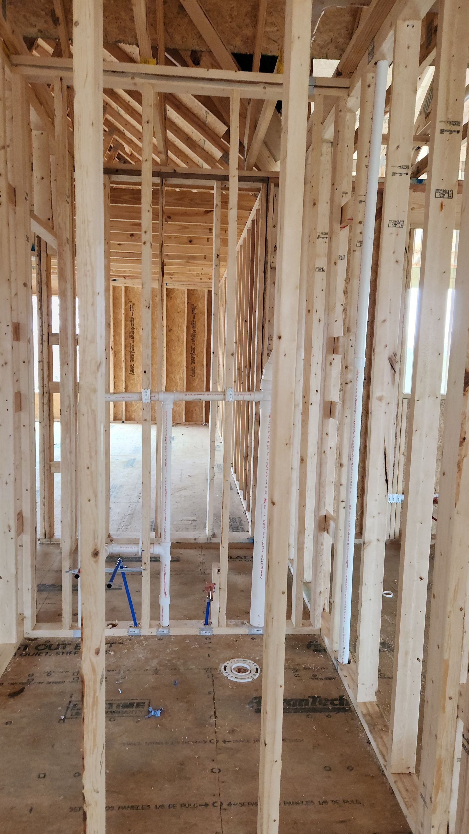 Unfinished interior of a house framed with exposed wooden studs and hallway framing.