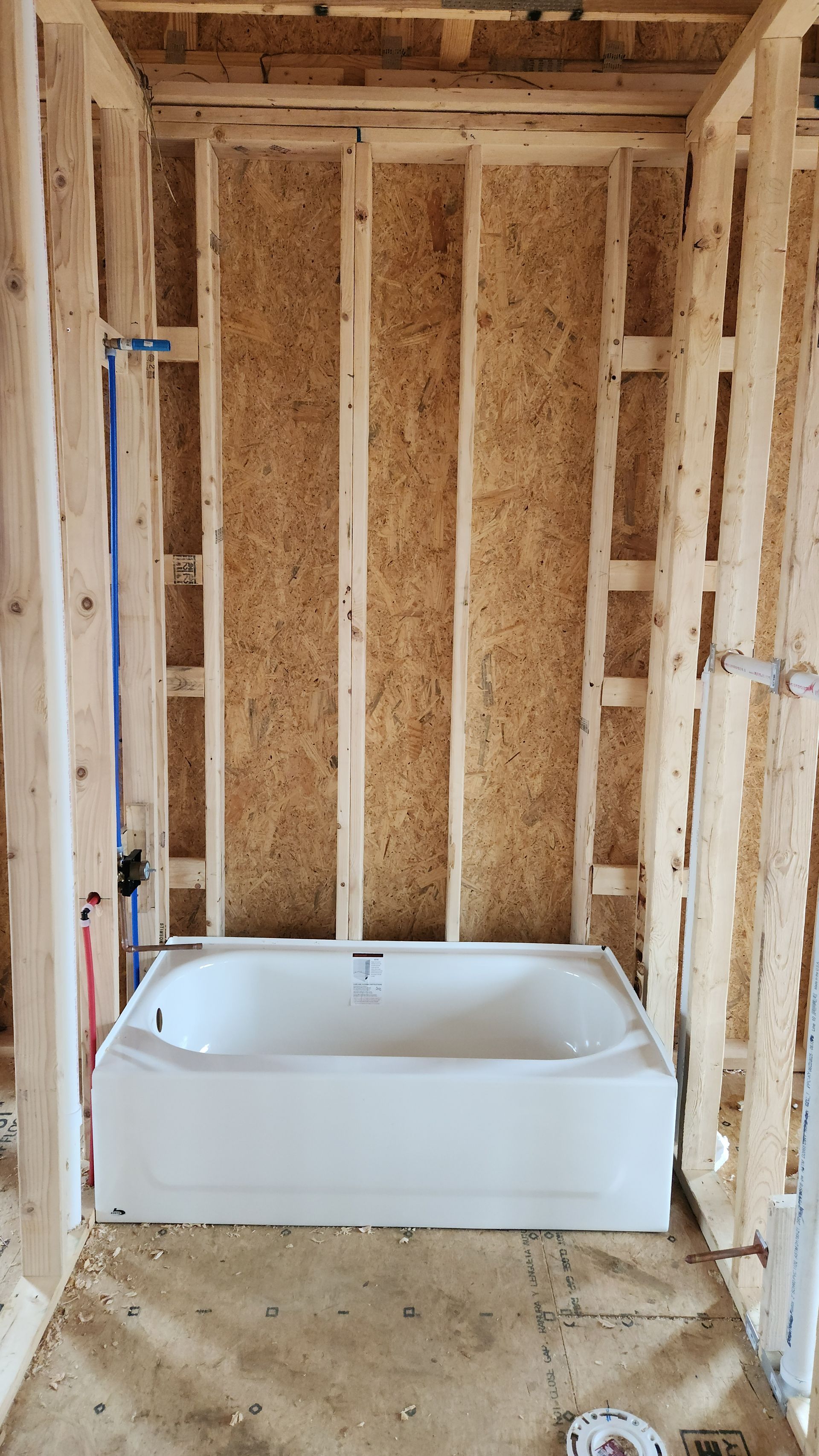 Unfinished bathroom with exposed wood framing and a white bathtub under construction.