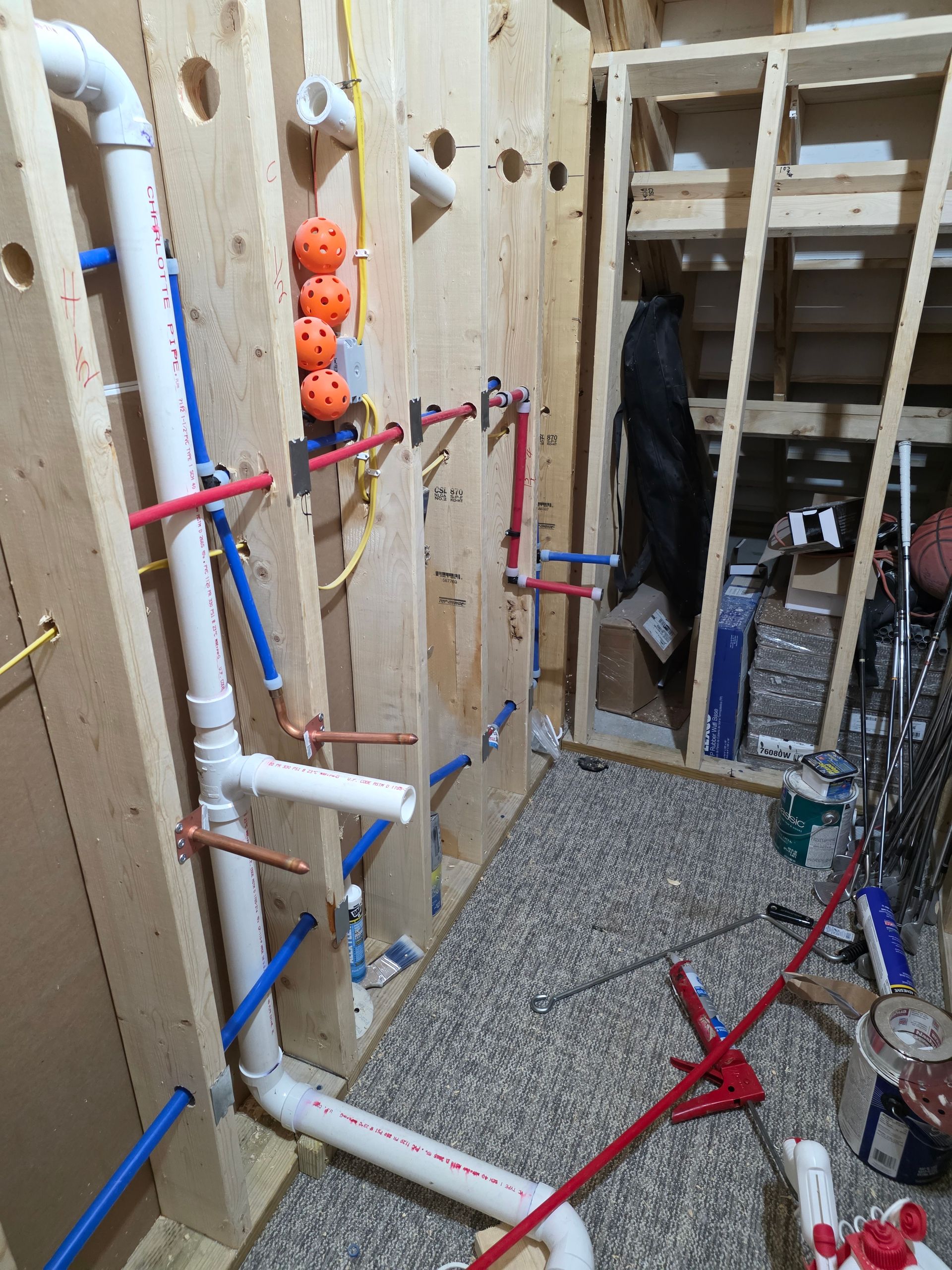 Narrow indoor obstacle course with PVC bars and orange handholds in a unfinished room