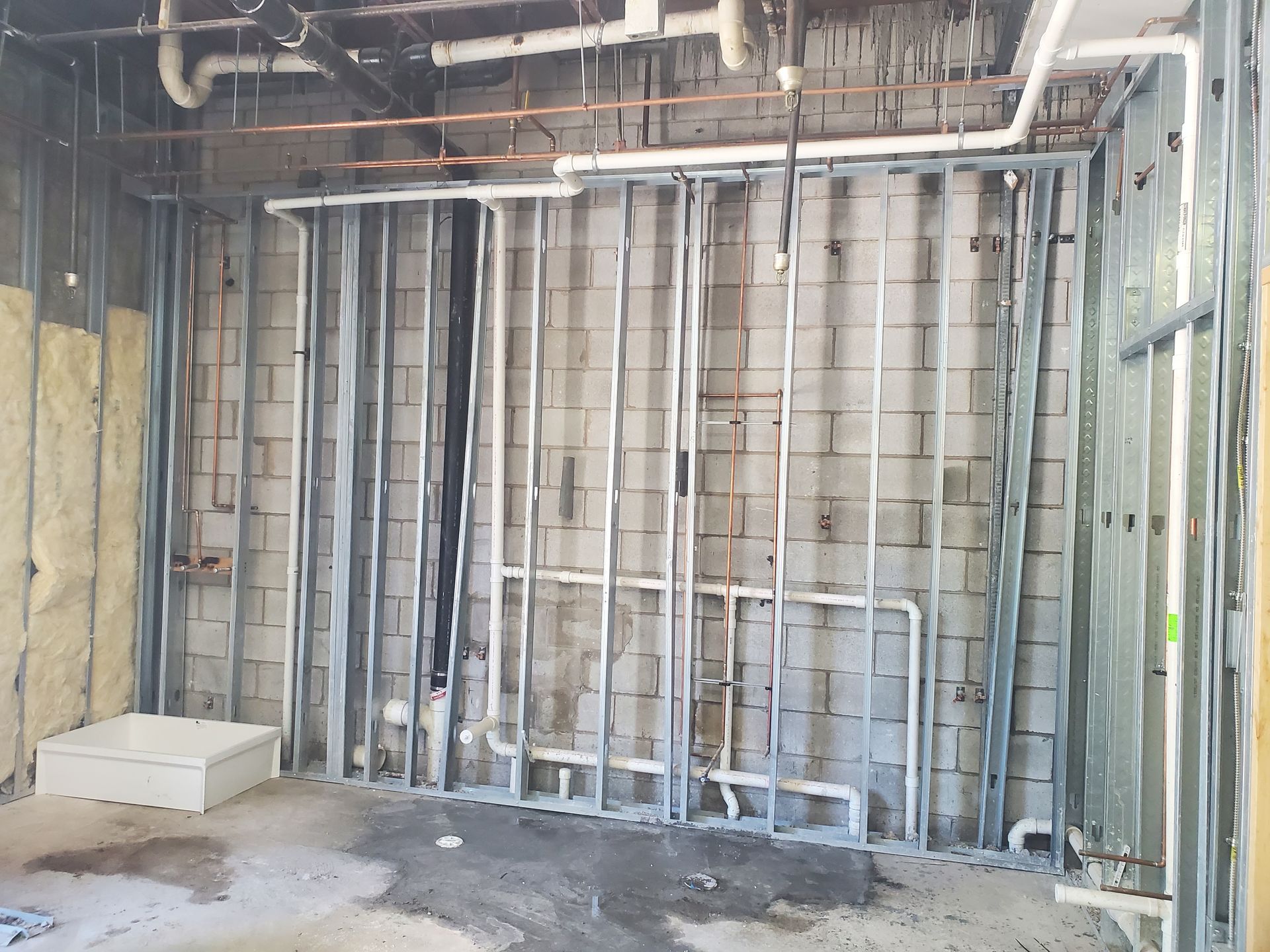 Interior wall with exposed metal studs, wiring, and insulation during renovation.