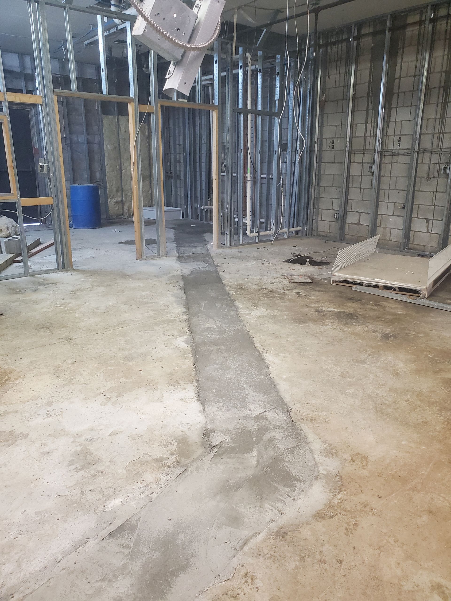 Unfinished basement with exposed framing, concrete floor, and stacked materials near a cinder block wall