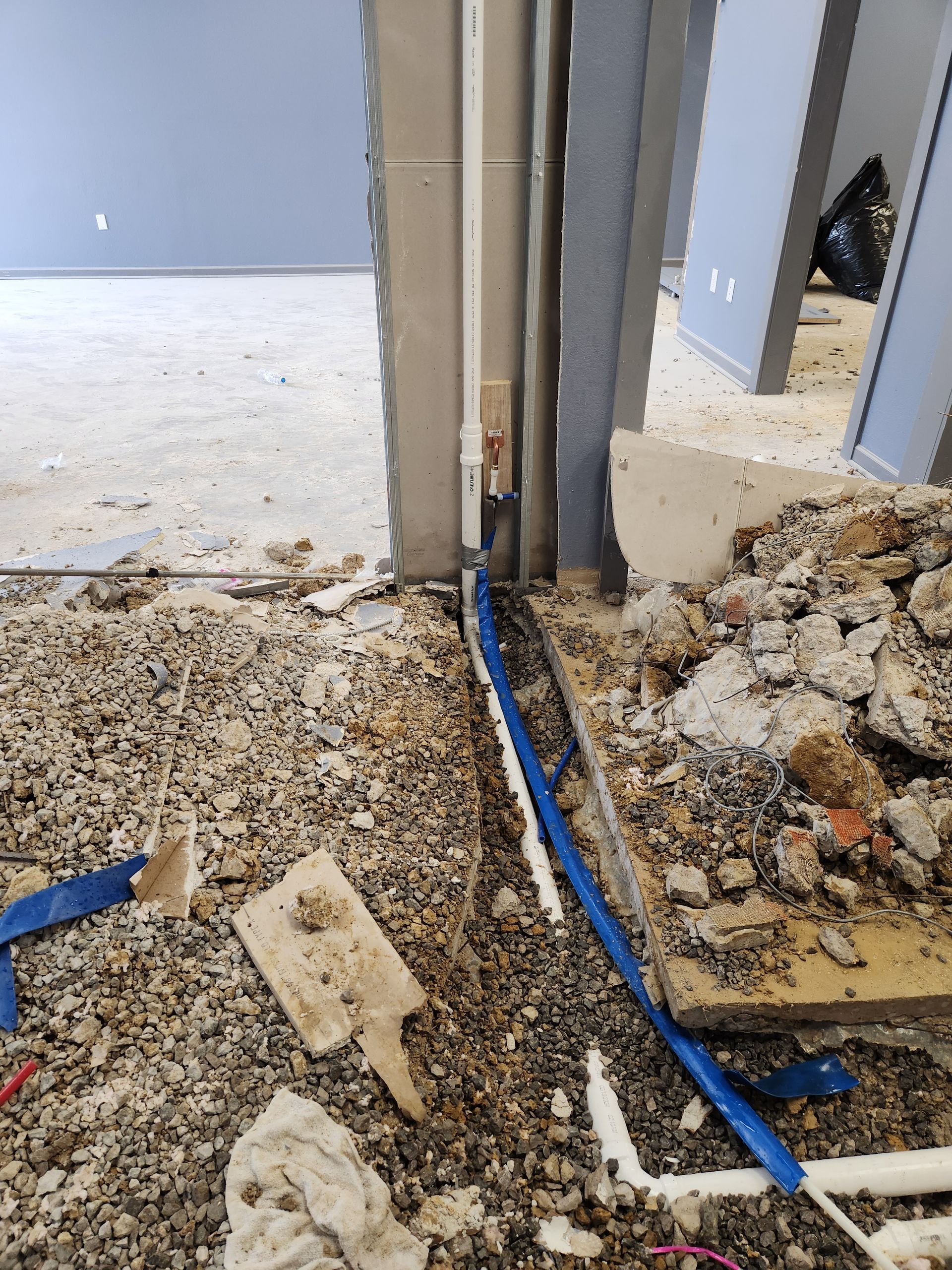 Debris-strewn construction floor with exposed blue cable and doorway framing damaged walls