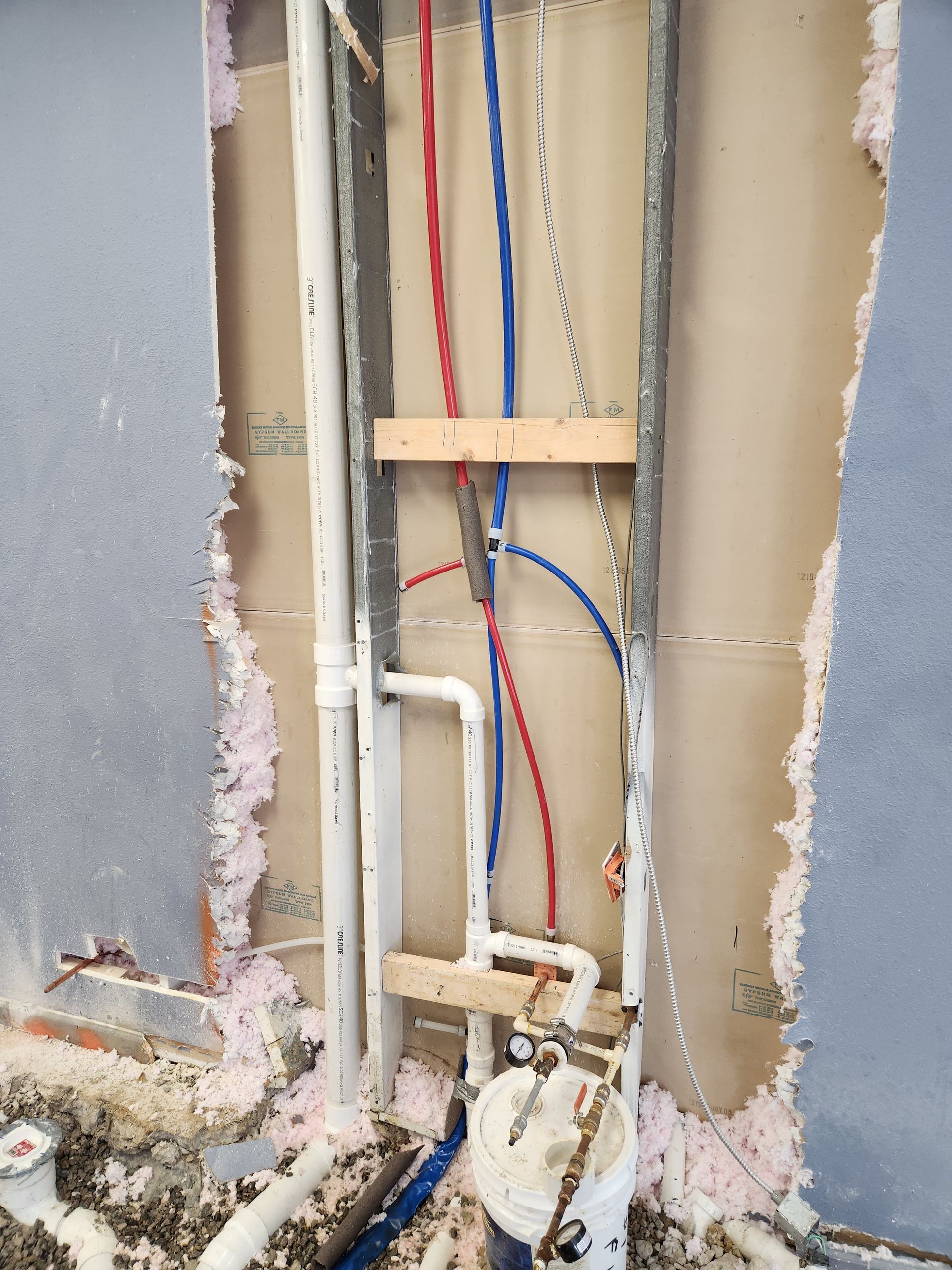 Exposed wall plumbing and wiring in a partially demolished interior wall