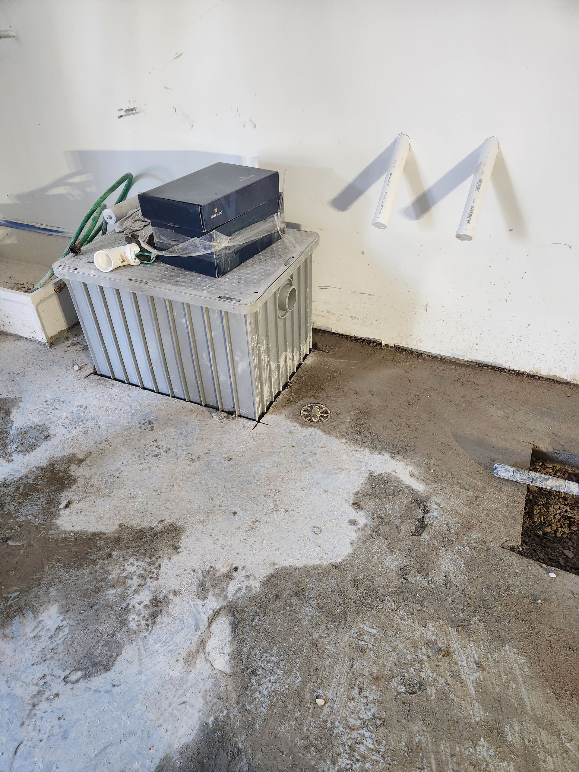 Cluttered floor with a small plastic crate and black toolbox against a stained wall in a bare room