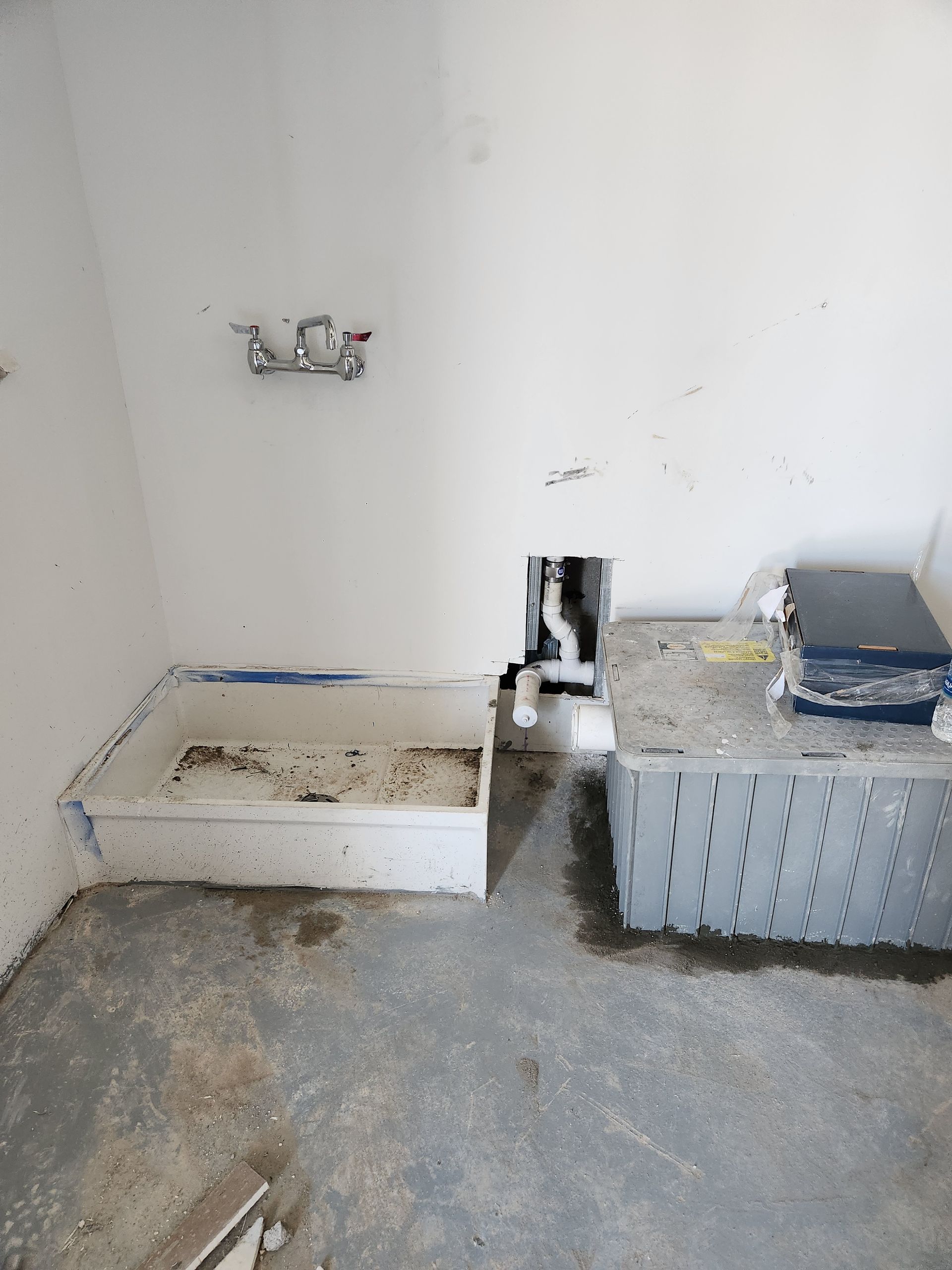 Empty room with unfinished fixtures, a small bench, and a washing machine against the wall.