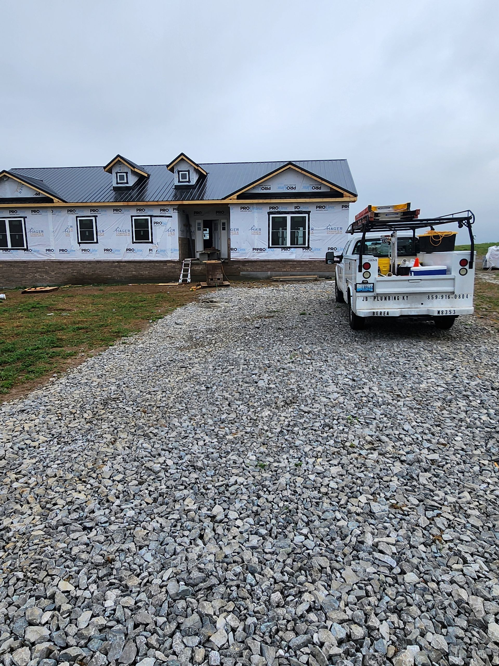 Construction truck on a gravel driveway in front of a house under construction