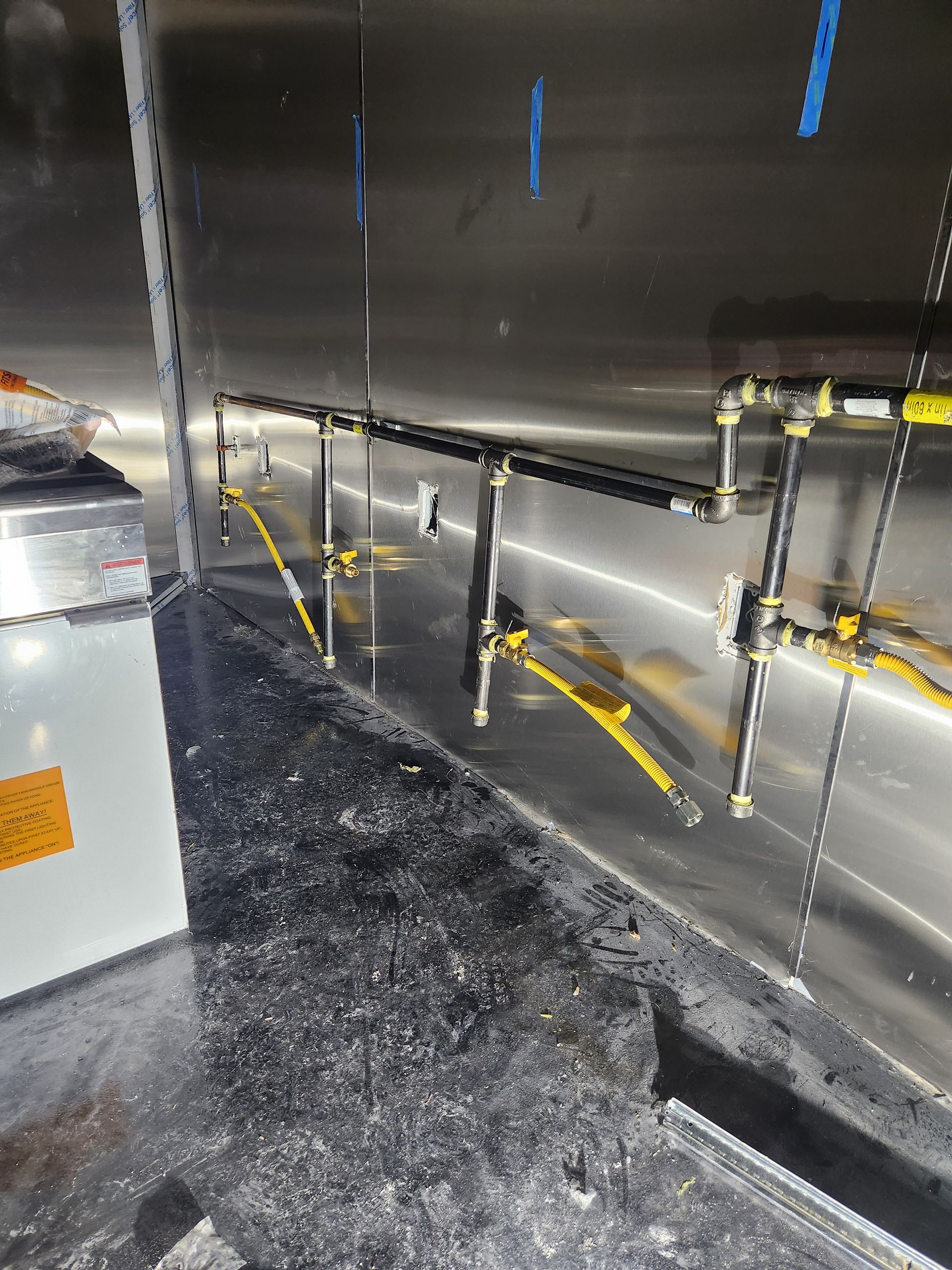 Metal wall with yellow handrails and a speckled floor inside an industrial interior.