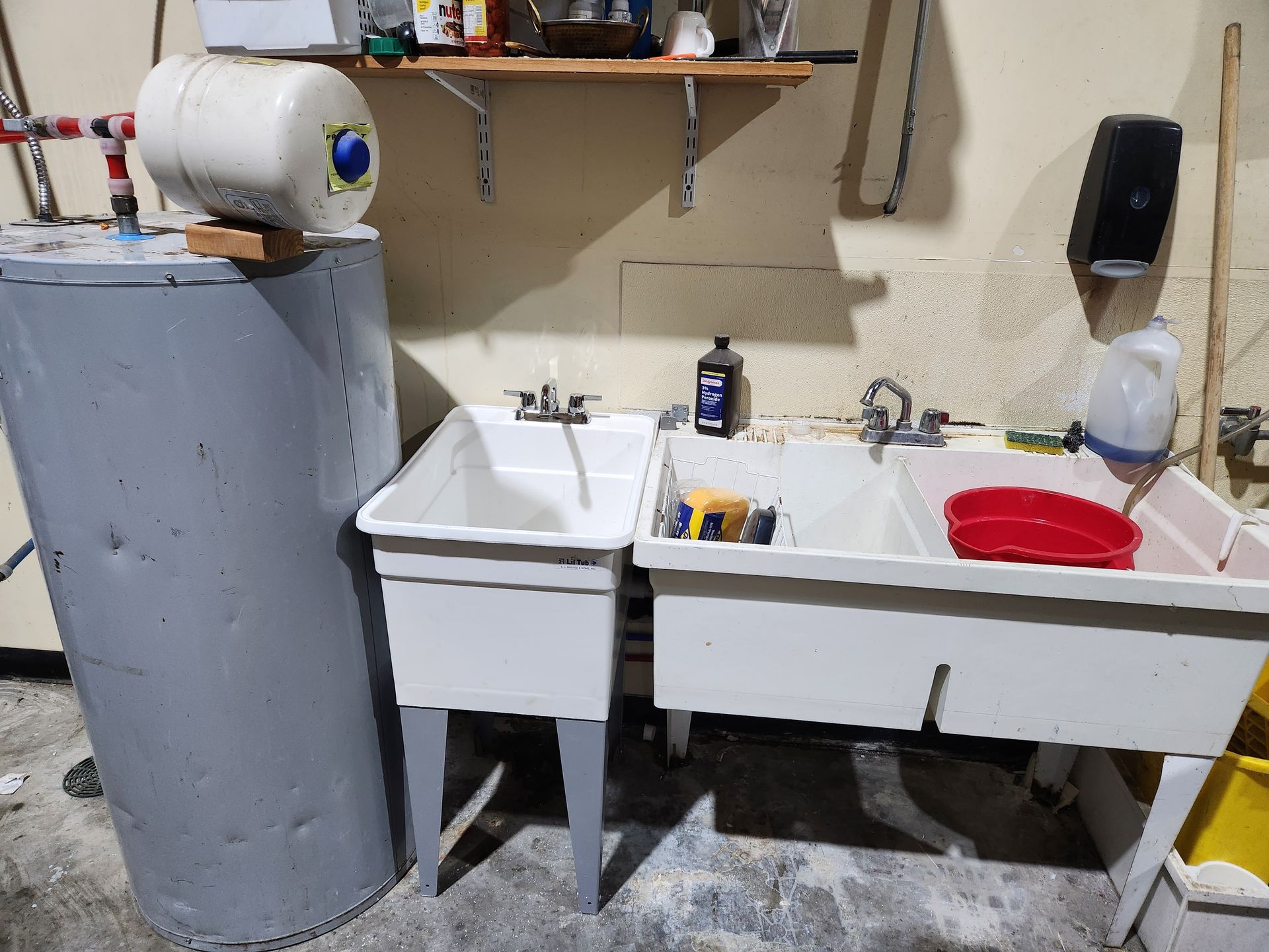 Laundry utility room with sink, washer, water heater, shelves, and cleaning supplies