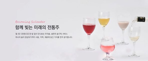다양한 색깔의 전통주가 담긴 와인잔. 한 잔에 병을 따라 붓고 있습니다.