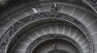A black and white photo of a spiral staircase in a building.
