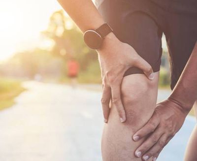 A person is holding their knee in pain.