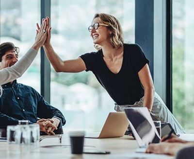A group of people are giving each other a high five in an office.