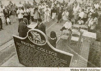 Graduation ceremony at Swayne College, with crowd gathered around a stage and chairs outdoors