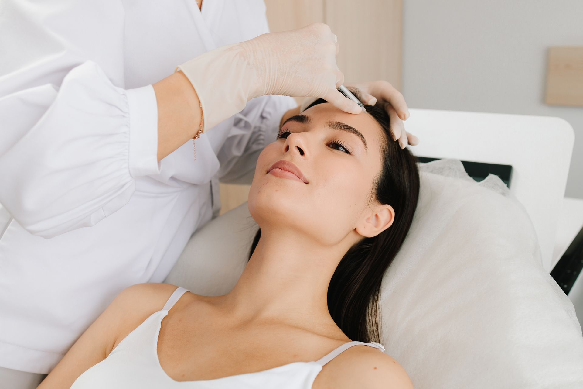 Cosmetologist applying treatment to a woman’s forehead in a spa setting