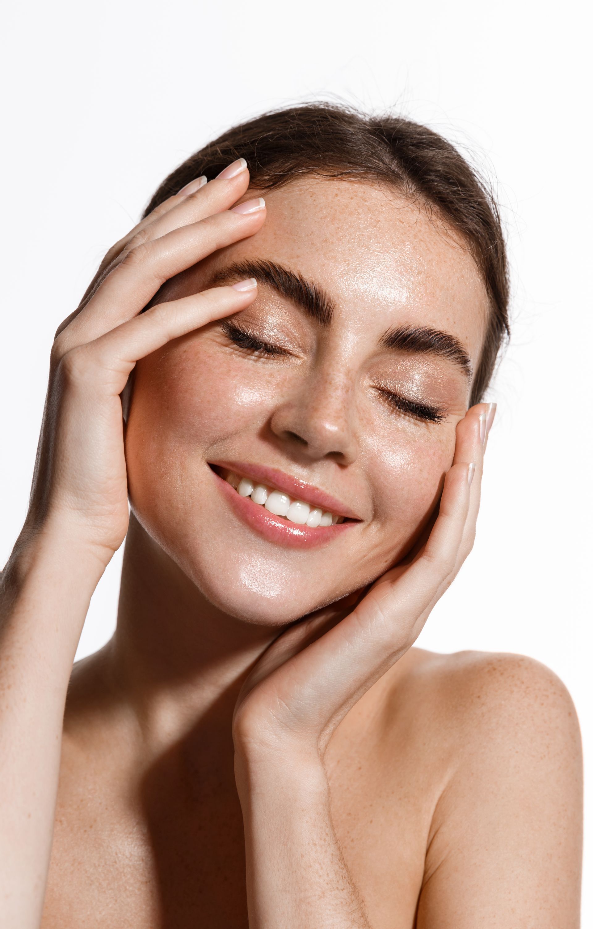a woman is smiling and touching her face with her hands .