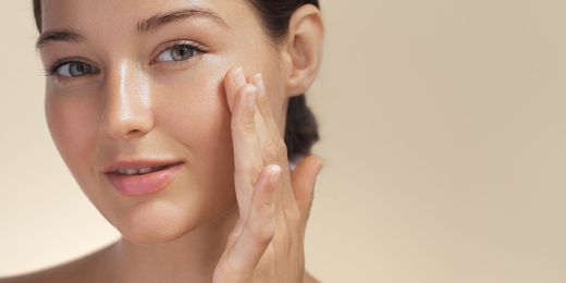 a woman is applying cream to her face .