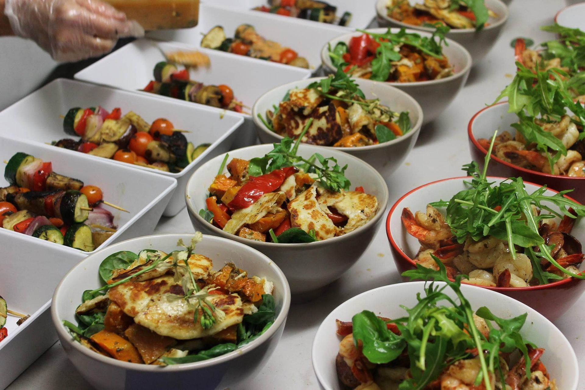 A table of chicken salads in smaller bowls lined up next to one another — Amanda Douglass Catering Service in Corlette, NSW