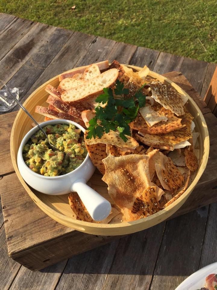 A Wooden Platter With Bread, Crackers, and Guacamole, on a Wood Surface — Amanda Douglass Catering Service in Corlette, NSW